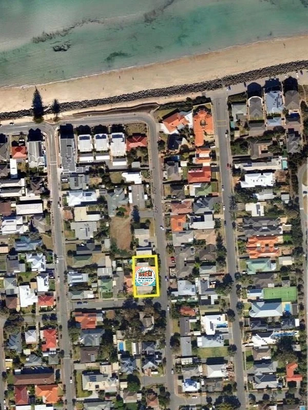 Aerial view of a coastal residential block; one property is outlined in yellow, near the beach.